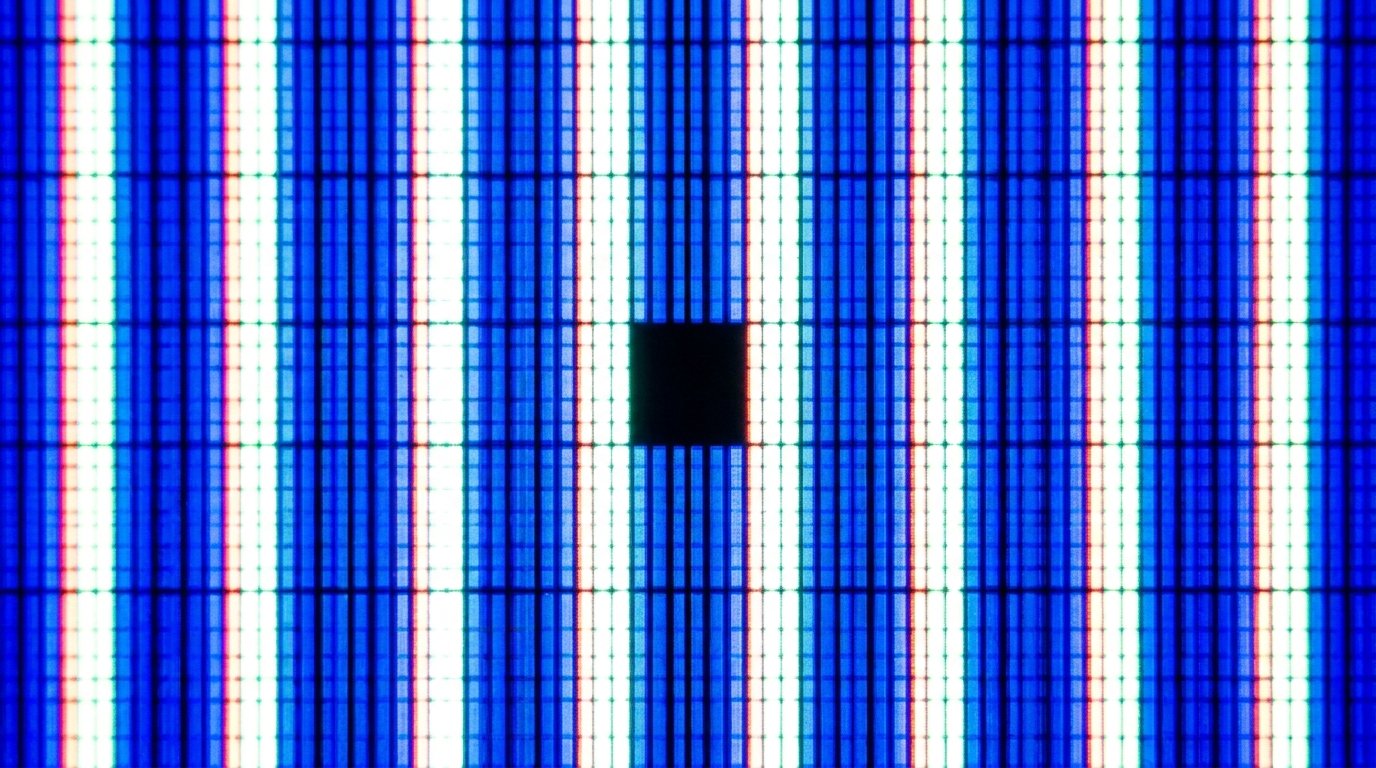 Close-up macro view of glowing monitor screen showing an isolated dark pixel defect surrounded by active pixels
